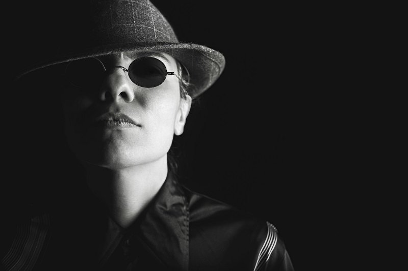 Imagen de una persona, en blanco y negro, con sombrero y lentes oscuros